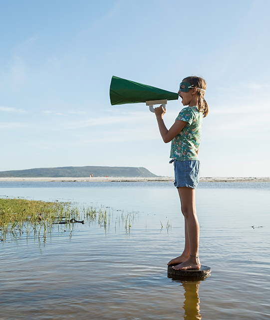 Girl at the beach shouting through a paper-made megaphone