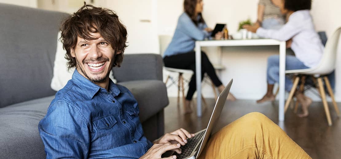 homme souriant assis avec un ordinateur sur les genoux