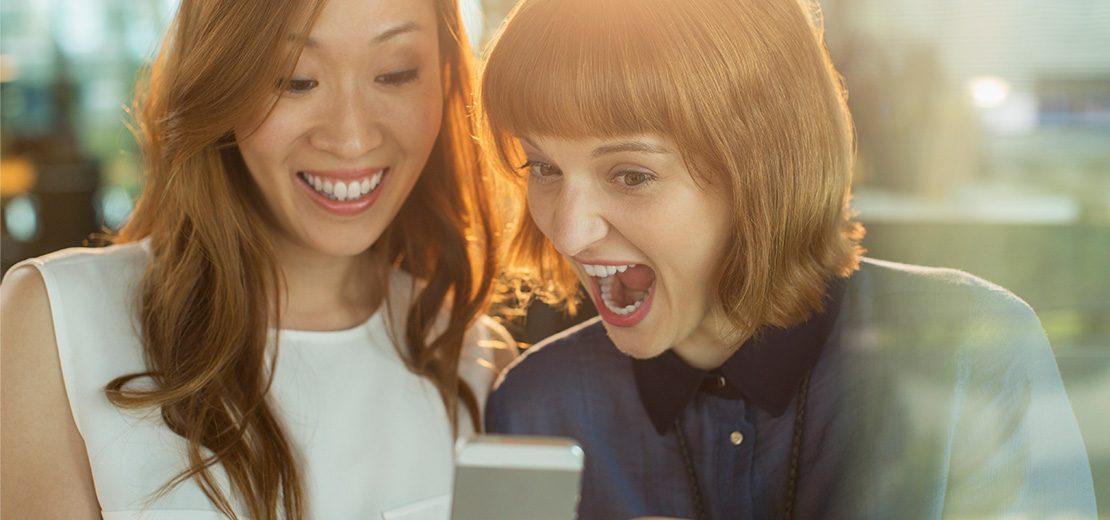 deux femmes s'amusent en regardant un smartphone