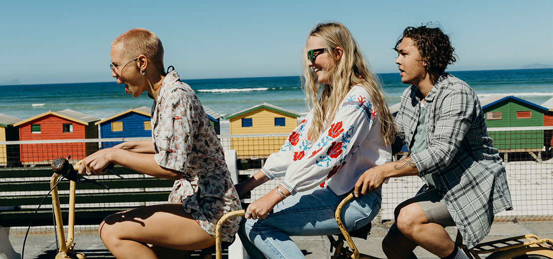 Three young adults on bikes at the beach